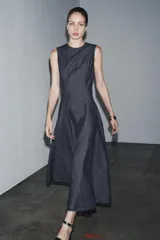 Vestido midi de denim azul oscuro, con cuello redondo y sin mangas. Corte entallado en la cintura y falda evasé. Cierre trasero con cremallera oculta.
