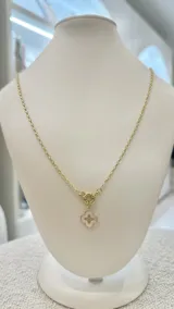 Collar dorado con cadena de eslabones y dije de trébol de cuatro hojas en nácar con detalles dorados.