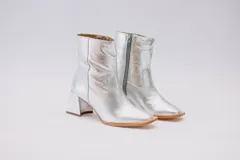 Botas plateadas de cuero con caña media, cierre lateral con cremallera y tacón geométrico.