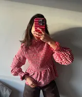 Blusa a cuadros rojos y blancos con cuello fruncido, mangas largas abullonadas y peplum.
