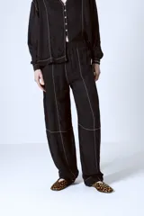 Pantalón negro de corte recto con costuras blancas a contraste.