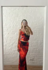 Conjunto de top corto con breteles finos y falda larga ajustada, ambos con estampado floral en tonos rojo y negro.