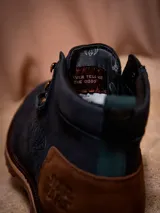 Botines de cuero color azul marino con detalles en marrón y suela marrón. Presenta el logo del Halcón Milenario en el lateral y el logo de Star Wars en el talón.