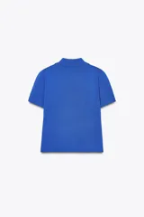 Chaqueta de punto azul con cuello solapa y manga corta. Tiene bolsillos delanteros de parche y cierre frontal con botones grandes con abalorios.