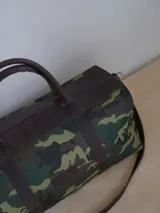 Bolso de lona azul con detalles en cuero marrón, doble asa de mano y correa bandolera ajustable. Incluye un neceser haciendo juego con cierre y logo de caballo bordado.