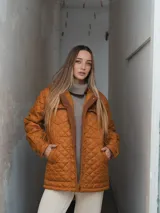 Campera acolchada color ladrillo con cuello marrón de pana, cierre frontal con botones a presión y bolsillos laterales.