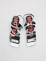Sandalias de cuero charol color borgoña con tiras finas, taco cuadrado bajo y cierre con hebilla en el tobillo. Interior con estampado del logo de la marca en color naranja.