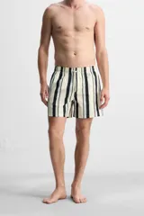 Short de baño blanco con rayas verticales negras y celestes, cintura elástica con cordón ajustable, bolsillos laterales y trasero.