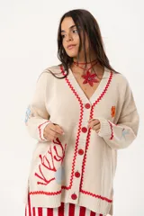 Saco oversize tejido con ilustraciones inspiradas en corales, peces, estrellas de mar y tortugas. El galón picot en rojo recorre el reborde de la cartera y los puños, mientras los botones a tono completan la armonía del diseño.