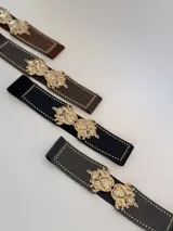Cinto elástico negro con apliques dorados en forma de corazón y tachas pequeñas.