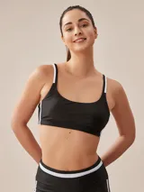 Top deportivo negro con tirantes finos blancos y banda inferior blanca.
