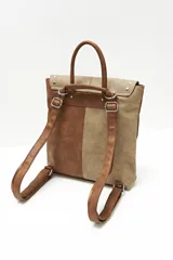 Mochila de cuero sintético color marrón y beige, con solapa con cierre de botón a presión y tachas plateadas.