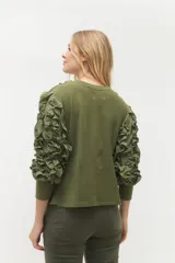 Remera negra de punto con mangas largas abullonadas con volantes.