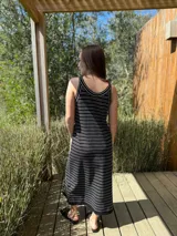 Vestido largo de punto, negro con rayas horizontales blancas, corte recto y sin mangas.