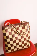 Bolso tipo tote de cuero tejido a mano con diseño a cuadros en color negro y tostado.