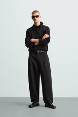 Polo de manga larga color negro, tejido en punto de algodón, corte relaxed fit, cuello solapa y cierre frontal con botonadura.