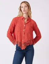 Camisa de algodón color naranja, con bordado suizo y encaje calado. Tiene cuello con solapa, botones frontales, mangas largas con terminación de encaje y ruedo asimétrico con galón de encaje.