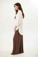 Sobrecamisa beige de corte recto, cuello mao y mangas 3/4. Presenta cierre frontal con botones de madera y bolsillos laterales.