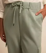 Pantalón cargo color verde claro, con cintura elástica ajustable con cordón, bolsillos laterales tipo cargo y corte holgado.