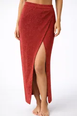 Pollera larga color rojo con brillo, de tejido de punto, con corte cruzado y abertura lateral.