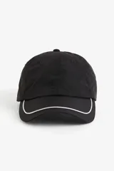 Gorra de nylon negra con ojales bordados y ribete blanco en la visera. Tiene trabilla ajustable con cierre de metal en la parte trasera y cinta antitranspirante de algodón.