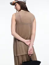 Musculosa sin mangas color gris, tejida en hilado con brillo sutil. De calce relajado y largo por debajo de la cadera, presenta aberturas laterales.