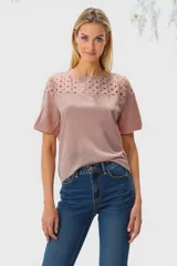 Remera color rosa pálido con detalle de encaje calado en la parte superior delantera y mangas cortas.