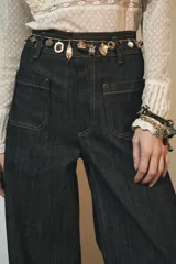 Pantalón de jean de tiro alto color negro con pierna ancha, bolsillos delanteros y traseros, y cierre frontal con cremallera y botón metálico.