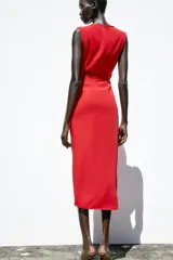 Vestido midi rojo de cuello redondo y sin mangas, con detalle de pliegues y fornitura en la cintura, y abertura frontal en el bajo.
