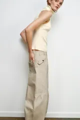 Pantalón cargo color beige de la colección Zara Woman, con tiro medio, cintura con trabillas, bolsillos delanteros y de plastrón con solapa en la pierna. Cierre frontal con cremallera y botón.