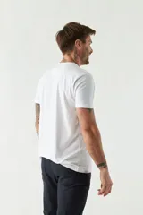 Remera blanca de algodón con estampado de una casa de playa en tonos azules. Corte regular, manga corta y cuello redondo.