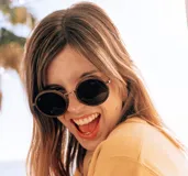 Lentes de sol redondos con marco de madera color marrón y lentes grises.