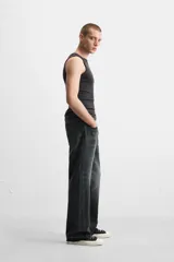 Pantalón de jean negro con efecto lavado, corte flare, cinco bolsillos, cierre frontal con cremallera y botón, y bajo con acabado irregular.