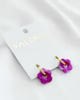 Aros colgantes con aro dorado y dije de flor de acrílico color violeta.