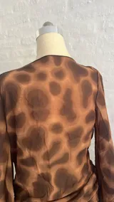 Minivestido marrón con estampado animal print, escote drapeado pronunciado y mangas largas acampanadas.