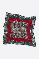 Pañuelo cuadrado con diseño de múltiples estampados animales en capas concéntricas. El centro presenta un estampado de leopardo en tonos rosa pálido y verde/negro. Le sigue un borde rojo con estampado de dálmata/leopardo pequeño, luego un borde verde con estampado de piel de serpiente, y finalmente un borde exterior con estampado de piel de serpiente en tonos blanco, negro y turquesa.