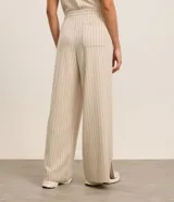 Conjunto deportivo de dos piezas color beige con finas rayas verticales negras. Incluye un chaleco corto con cuello en V y un pantalón palazzo con cintura elástica ajustable.