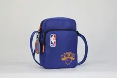 Morral cruzado de nylon color azul, con logo de la NBA y el escudo del equipo New York Knicks en color naranja. Posee correa regulable y un dije colgante con el logo del equipo.