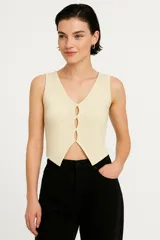 Top sin mangas color crema, de punto crochet con rayas verticales, cuello en v y cierre frontal con broches.