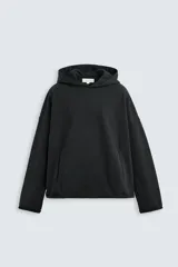 Sudadera con capucha negra, de corte oversize, confeccionada en tejido de algodón con interior en rizo. Cuenta con manga larga, bolsillos frontales tipo canguro, efecto lavado y acabados irregulares con vuelta.