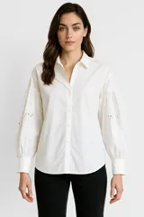 Camisa blanca de algodón con cuello clásico, abotonada al frente y mangas largas abullonadas con bordados.