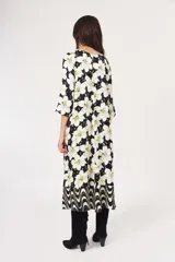 Vestido midi con estampado de flores blancas sobre fondo negro, mangas 3/4 y corte evasé.