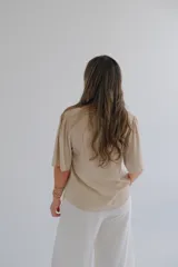 Blusa beige de mangas cortas con volados y escote en V.