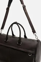 Bolso de viaje negro con acabado grabado, compartimento principal con cierre de cremallera, bolsillo interior con cierre de cremallera, bolsillo frontal con cierre de cremallera, asa de hombro removible y ajustable.