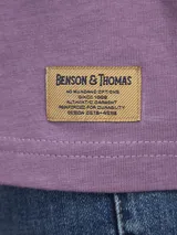 Remera de algodón color azul marino con un estampado gráfico abstracto en la espalda que incluye un círculo azul y formas onduladas en tonos de azul y gris. En la parte superior de la espalda lleva texto impreso.