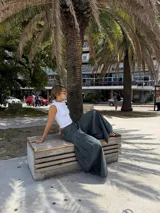 Pantalón de jean ancho, color verde oscuro o gris verdoso, de tiro alto con pliegues frontales y corte extremadamente holgado.