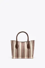 Bolso estilo bandolera con estampado a rayas verticales color marrón y crudo. Tiene asa de mano y asa fina extraíble con detalles metálicos. El bolso interior es a contraste de materiales con cierre mediante cremallera metálica. Cierre imantado.