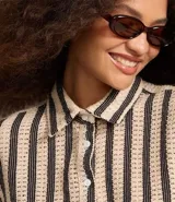 Camisa corta de algodón a rayas verticales color beige y negro, con cuello clásico, manga corta y cierre frontal con botones.