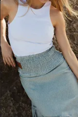 Pollera midi celeste con finas rayas verticales blancas, cintura elastizada con detalle de etiqueta de cuero marrón en el frente.