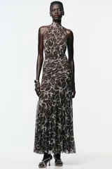 Vestido largo marrón con estampado de flores blancas, cuello halter con lazada, detalle de frunces y forro interior combinado.